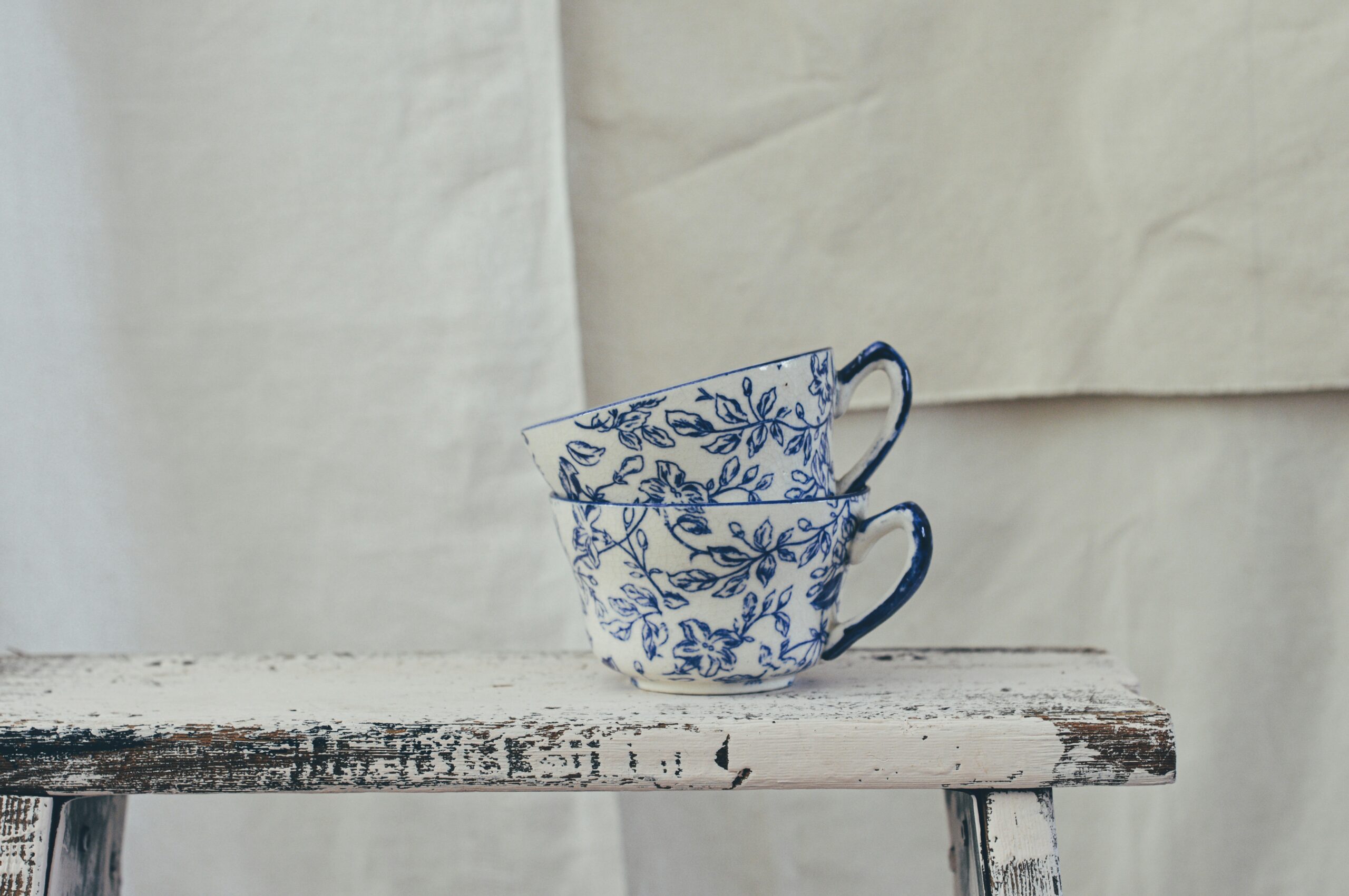 white and blue floral ceramic mug on white table